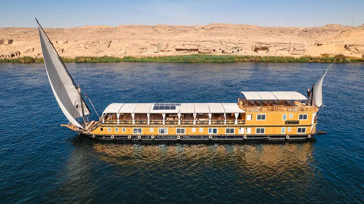 Traditional dahabiya sailboat on a luxury Nile river cruise between Aswan and Luxor at golden hour