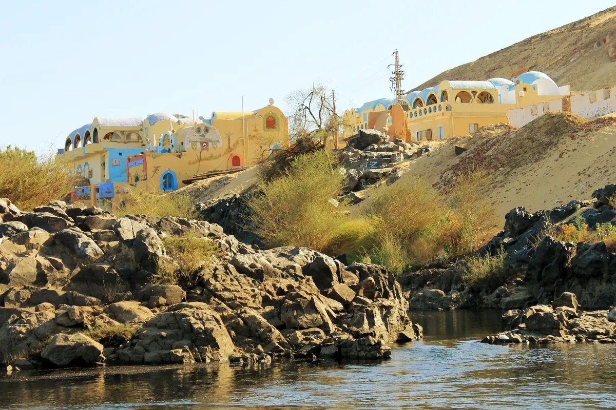 Colourful Nubian houses on the bank of the Nile at Aswan, seen from a Nile cruise or felucca